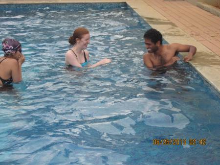 Vivek holding on to the side of the pool. Madeleine laughing.